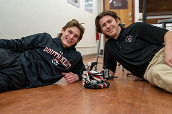 Two students posing with their robotics project. Links to Gifts by Will