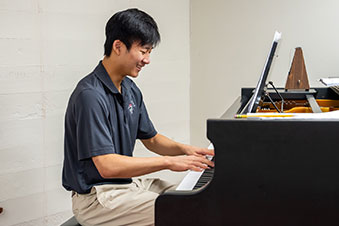 A student smiles as he plays the piano. Links to Gifts That Protect Your Assets
